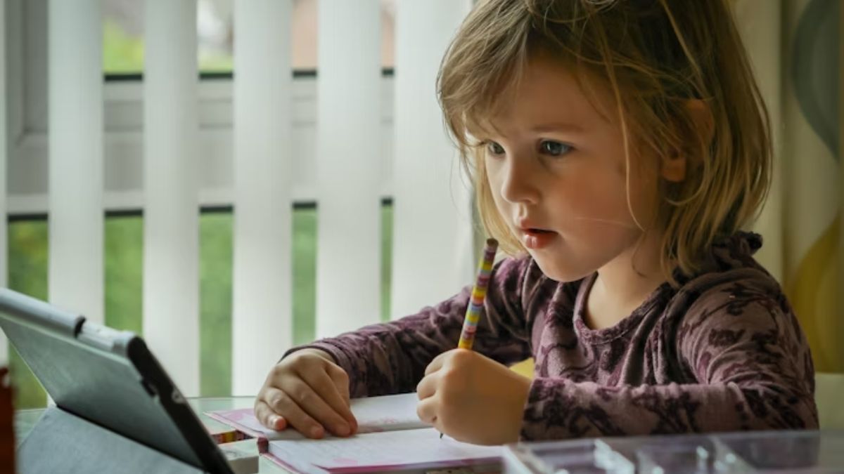 A girl focused in a sunlit room, learning to draw and write in cursive with her pens and paper in a colorful photo.