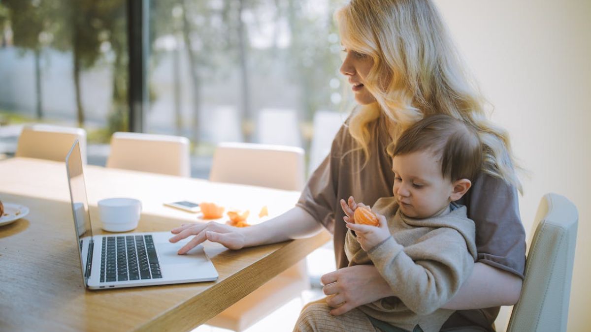 Blonde woman holding her child at a dinner table in a sunlit room while browsing ABA therapy centers.