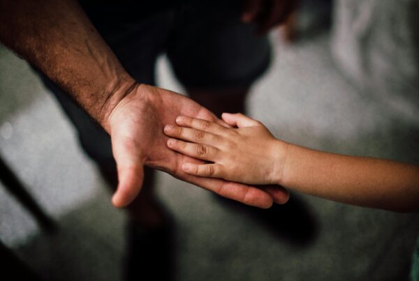 Hands visible at dusk, with a father reaching out to his child.