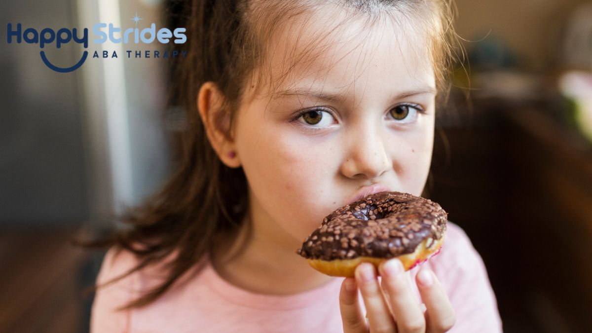 Autism and eating too much, a young girl munches on a donut while holding a serious expression.