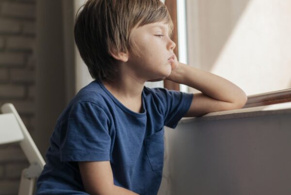 Can non-verbal autism be cured, a young boy in a blue shirt stares pensively out of a window.