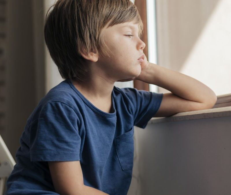 Can non-verbal autism be cured, a young boy in a blue shirt stares pensively out of a window.