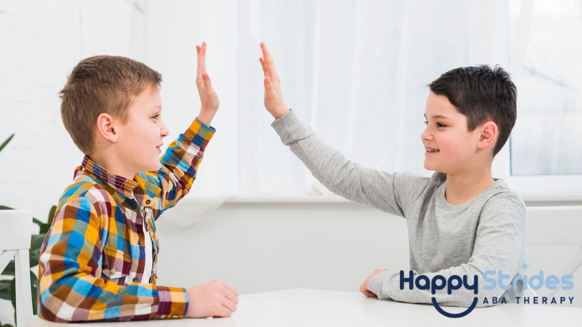 Two boys in a bright, white room share a joyful moment by giving each other a high five, illustrating nonverbal communication in autism.