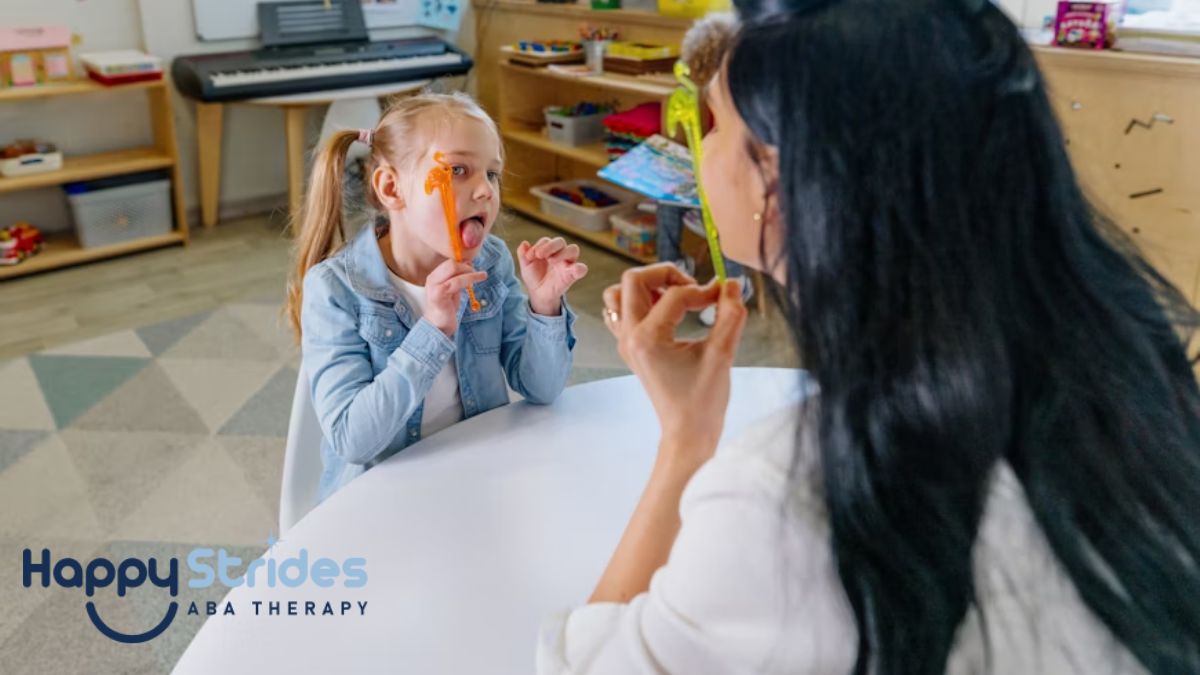 A female therapist, her back to the camera, teaches a child in a therapy room filled with toys and sensory devices during a prompt therapy session for autism.