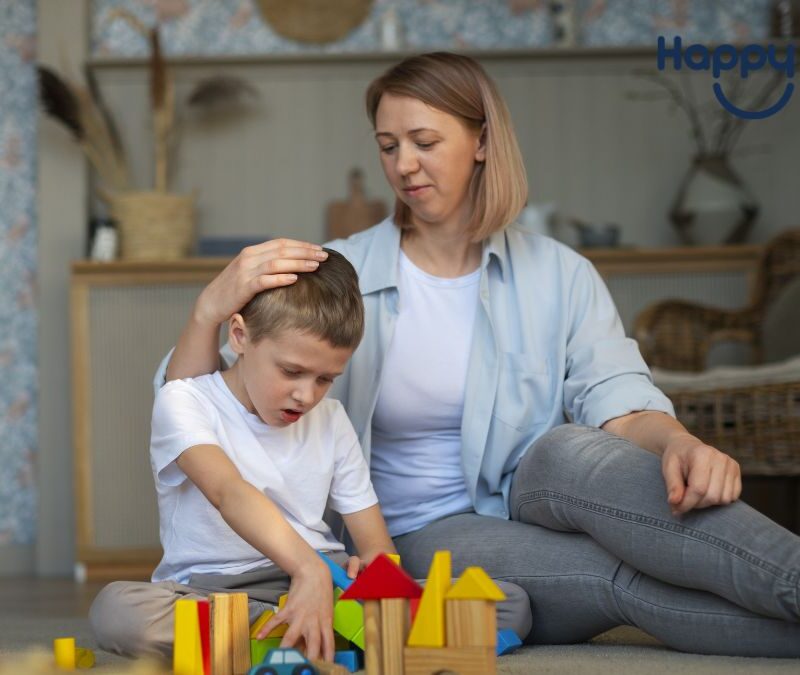 A female therapist or parent gently buzzes a young boy’s hair while holding him close during a play-based autism therapy session.