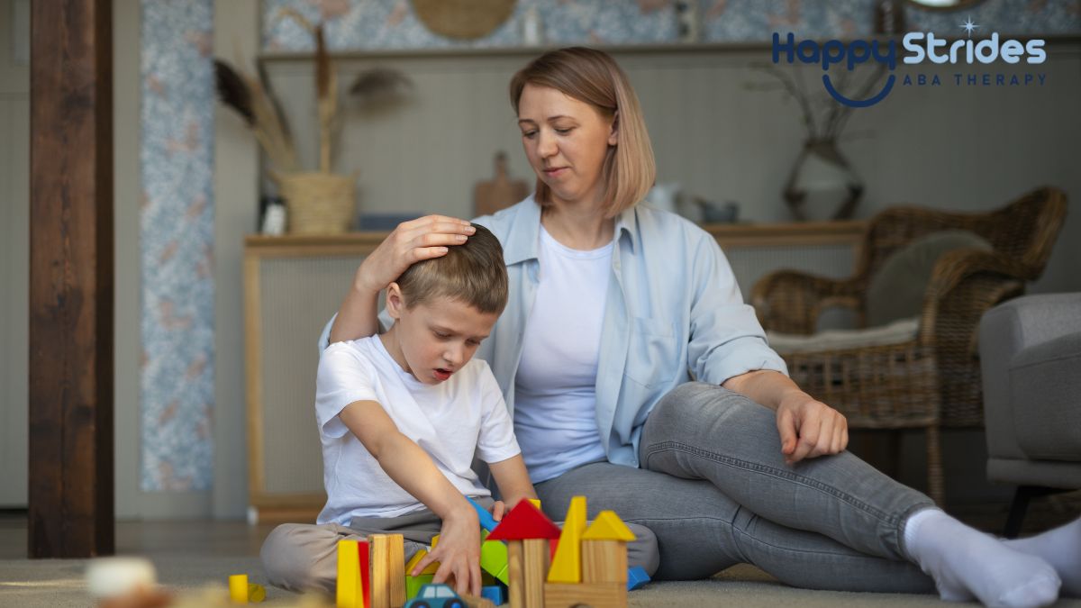 A female therapist or parent gently buzzes a young boy’s hair while holding him close during a play-based autism therapy session.