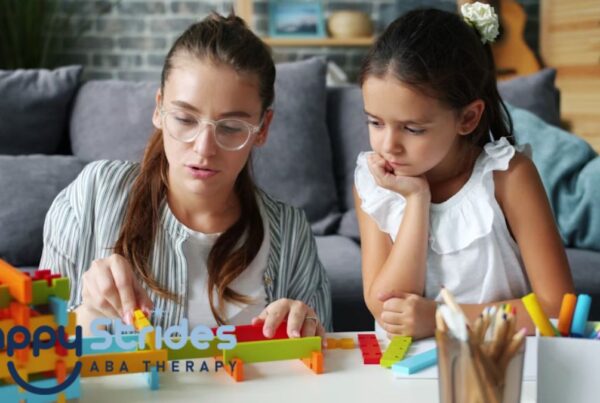 An adult guides a young child in a puzzle game on the coffee table during at-home autism therapy, while they sit on the living room floor.