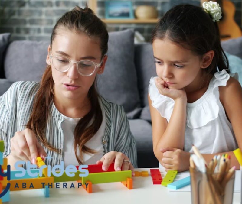 An adult guides a young child in a puzzle game on the coffee table during at-home autism therapy, while they sit on the living room floor.