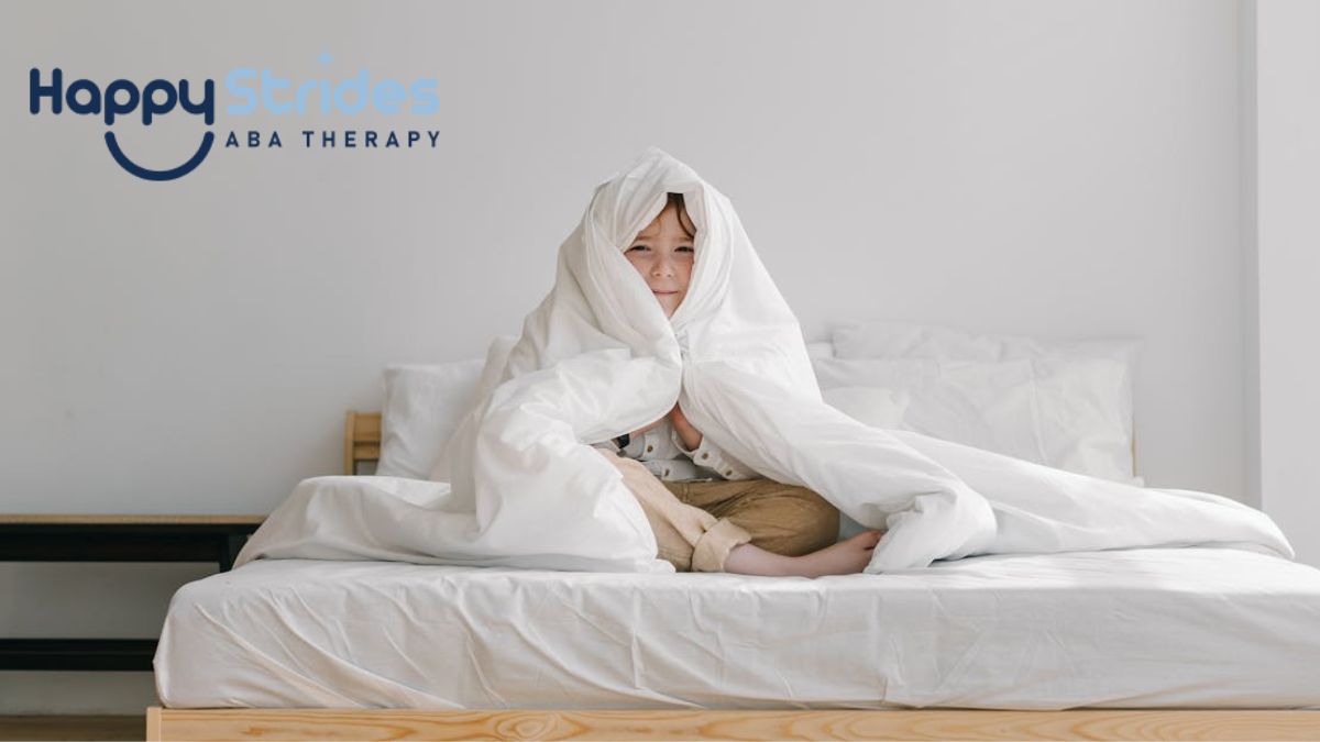 A young boy with autism, showing hyposensitivity, sits on his bed while soothing himself with a weighted blanket.