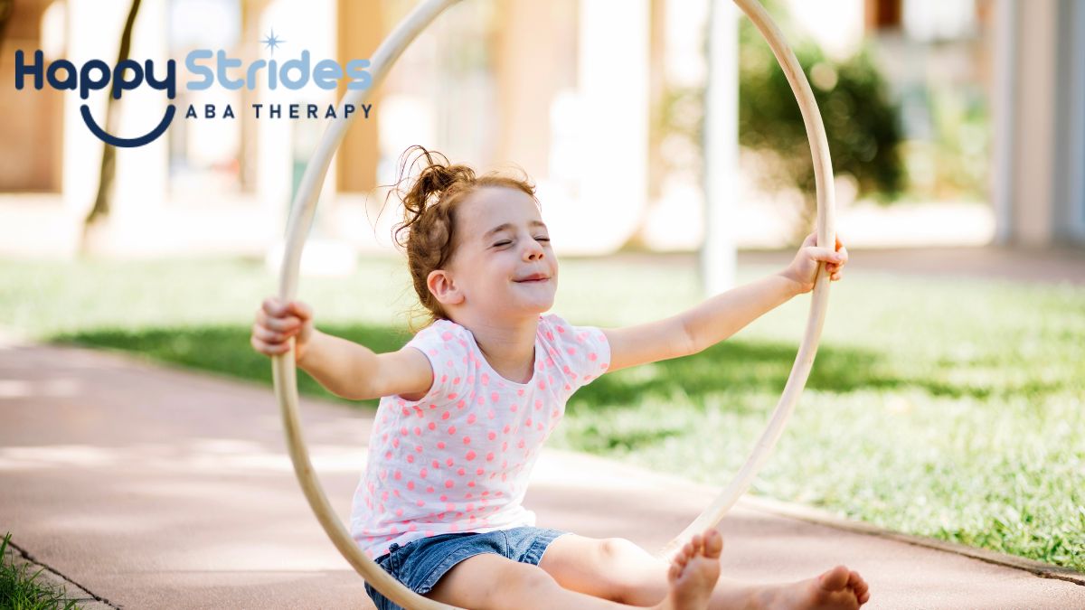A young girl with autism, showing hyposensitivity, plays holds a hula hoop outdoors fpr a physical and imaginative play.