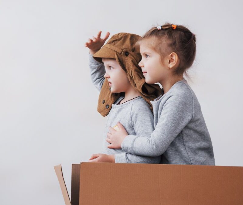 Two children in profile engage in a pretend play activity, imagining themselves as aviators, illustrating social interaction and transitional play often encouraged in autism support.