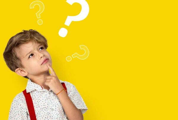 A boy with autism looks upward to the right with a wondering expression, while illustrated question marks appear above him to reflect his thoughts about executive functioning.