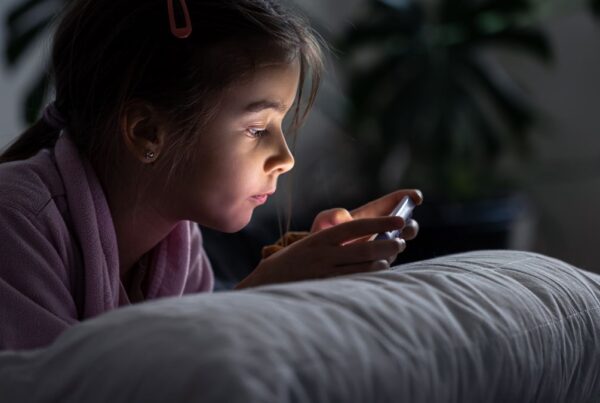 Girl staying up late reading from a smartphone, illustrating sleep challenges often discussed in autism.