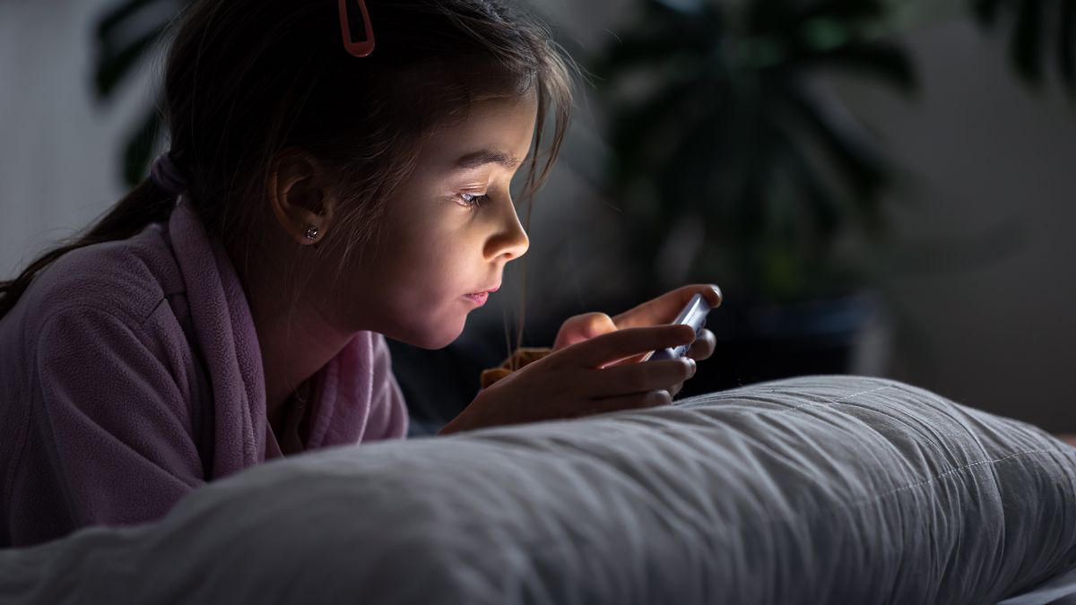 Girl staying up late reading from a smartphone, illustrating sleep challenges often discussed in autism.